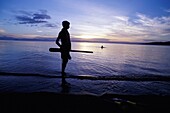 Silhouetted Boy Standing On Edge Of Lake