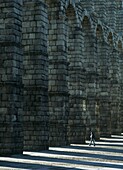 Woman Walking Through Arch Of Roman Aqueduct