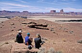 Drei Wanderer entspannen sich auf einem Felsen am White Rim