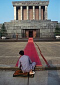Eine Person legt einen roten Teppich vor dem Ho-Chi-Minh-Mausoleum aus, Rückansicht