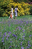 Zwei Frauen und ihre Tochter spazieren neben Glockenblumen in Stourhead Gardens