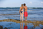 Paar in Badekleidung umarmt Blick auf den Ozean am Praia Do Forte, Bahia, Brasilien