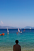 Mann beobachtet Menschen beim Windsurfen, Rückansicht, Lefkas, Ionische Inseln, Griechenland