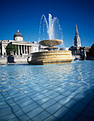 Springbrunnen am Trafalgar Square mit National Gallery und St Martins In The Fields Church, London.