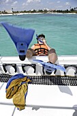 Mann mit Schnorchelausrüstung springt in Boot an der Maya-Riviera, Yucatan-Halbinsel, Staat Quintana Roo, Mexiko