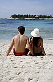 Junges Paar sitzt am Strand der Riviera Maya, Rückansicht, Halbinsel Yucatan, Staat Quintana Roo, Mexiko