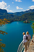 Two Tourists Looking At Lake Bled From Castle Terrace