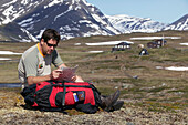 Hiker Checking Map Sitting In Valley, Kungsleden Trail,Abisko,Sweden