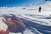 Person, die am Hang eines schneebedeckten Berges steht, Grimselpass, Goms Valley, Schweiz