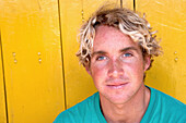 Porträt eines mittelgroßen Mannes vor einer gelben Wand, der irische Surfer Cain Kilcullen