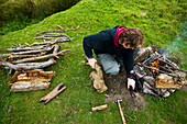 Mann bereitet Lagerfeuer auf einem Feld vor, Dartmoor National Park,Postbridge,Yelverton,Devon,Uk
