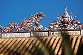 Detail des Gebäudes mit Drachen durch Palmblätter gesehen, Verbotene Stadt, Hue City, Vietnam