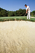 Mann spielt Golf in der Nähe der Sanddüne