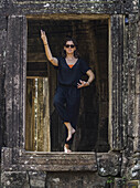 Eine Frau steht in einer Yoga-Pose in einer Öffnung des Bayon-Tempels, Angkor Thom; Krong Siem Reap, Provinz Siem Reap, Kambodscha.