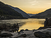 Ein goldener Sonnenuntergang spiegelt sich im ruhigen Wasser mit schemenhaften Bergen; Provinz Luang Prabang, Laos