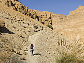 A Young Woman Walks On A Trail Through The Rugged Hills Of Ein Gedi Nature Reserve, Dead Sea District; South Region, Israel