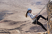 Eine junge Frau, die sich in den Ramon-Krater abseilt, Ramon-Naturschutzgebiet; Mitzpe Ramon, Südbezirk, Israel