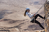 A Young Woman Rappelling Into Ramon Crater, Ramon Nature Reserve; Mitzpe Ramon, South District, Israel