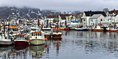 Boats In The Harbour And Buildings On The Shore With Low Cloud Hanging Overhead; Lofoton Islands, Nordland, Norway