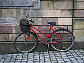 Ein rotes Fahrrad, geparkt vor einer Mauer aus Steinblöcken; Stockholm, Schweden