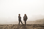 Zwei Freundinnen stehen redend an einem Strand im Nebel; Prince Edward Island, Kanada