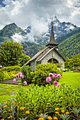 Mittelalterliche Kirche Les Praz de Chamonix und Blumengarten mit der Aiguille Dru im Hintergrund; Chamonix-Mont-Blanc, Haute-Savoie, Frankreich.