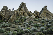 Couple standing on rocks of the Alabama Hills after sunset; California, United States of America