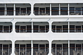 Drei Ebenen an der Seite eines Bootes mit Stühlen auf den Balkonen und Glaswänden; Kotor, Opstina Kotor, Montenegro.