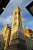 Large decorative cathedral with tower and dome with blue sky and clouds glowing orange at sunset