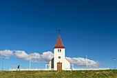 Mädchen geht an kleiner Kirche vorbei; Langaholt, Island