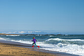 Girl running from waves on Langaholt beach; Langaholt, Iceland