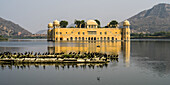 Jal Mahal Palace, made of red sandstone, sitting submerged in Man Sagar Lake; Jaipur, Rajasthan, India