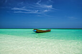A boat sits in the shallow turquoise waters in a tropical paradise; Andaman Islands, India