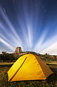 Leuchtend gelbe Zelt- und Sternenspuren, Devils Tower National Monument; Wyoming, Vereinigte Staaten von Amerika