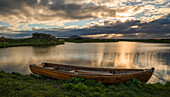 Ein Boot liegt im ruhigen Myvatn-See, Nordisland, bei Sonnenuntergang; Island