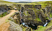 Eine Touristin steht auf einem Aussichtspunkt auf einer Klippe im malerischen Tal von Fjadrargljufur in Südisland; Island