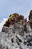 A female tourist poses for a portrait on the top of a rock formation in Western Iceland, Snaefellsnes peninsula; Iceland