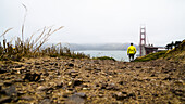 A man walking near the Golden Gate Bridge on a foggy day; San Francisco, California, United States of America