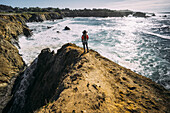 A woman stands looking out along the Russian Gulch Headlands, Mendocino county; California, United States of America