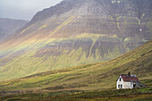 Faint rainbow over an abandoned Iceland homestead; West Fjords, Iceland