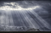 Dramatic sunlight beams punch through the clouds along the South coast of Iceland creating an amazing scene; Iceland