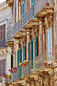 Facade of a residential building with shutters and balconies; Syracuse, Sicily, Ortigia, Italy