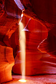 Upper Antelope Canyon with a beam of sunlight shining through a hole resembling a spotlight to the ground; Arizona, United States of America