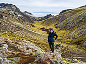 Eine Frau steht in der zerklüfteten Landschaft von Südisland; Grimsnes- og Grafningshreppur, Südliche Region, Island
