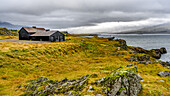 Ein Haus mit Blick auf das Wasser entlang der Küstenlinie des Fjords Berufjorour; Djupivogur, Ostregion, Island