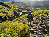 Eine Frau wandert auf dem Glymur-Wanderweg. Glymur ist der zweithöchste Wasserfall in Island mit einer Kaskade von 198 Metern; Hvalfjardarsveit, Hauptstadtregion, Island