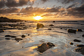 Beautiful sunset on the Pacific ocean photographed from a rocky beach; Atacama, Chile