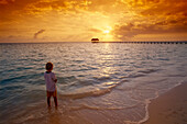 Junge am Strand bei Sonnenaufgang