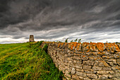 Stone wall leading to the Cleadon Windmill ruin, built in the 1820's at the the highest part of the Cleadon Hills and previously used as an artillery training base during WWI, on a stormy day; South Shields, Tyne and Wear, England, United Kingdom
