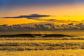 View of breaker waves and surf with low lying clouds in the sky at sunset; South Shields, Tyne and Wear, England, United Kingdom